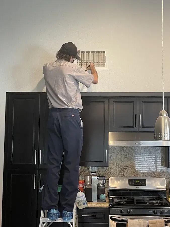 Technician inspecting an air vent during HVAC service in Cherry Hills Village